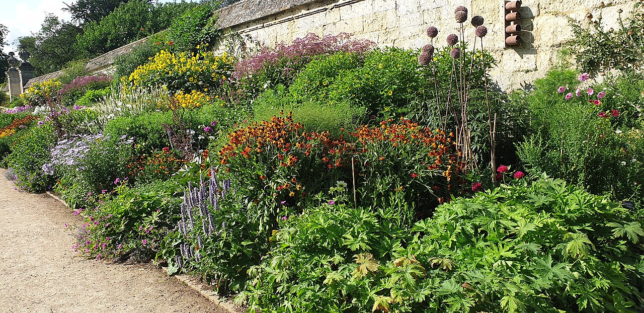A long flower border against a stone wall